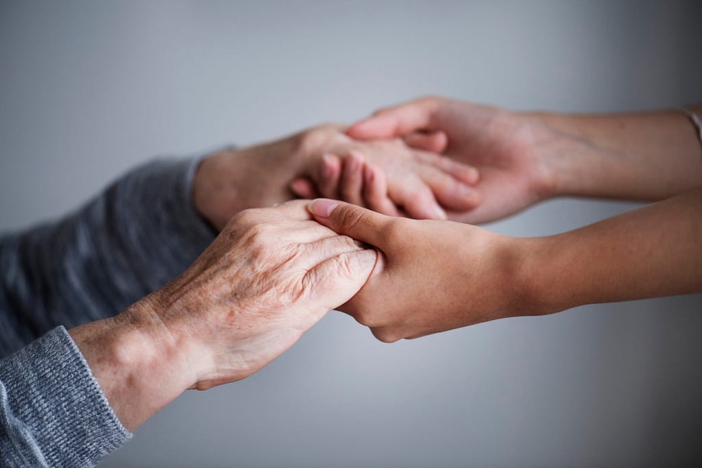 Hände einer älteren und einer jüngeren Person als Zeichen der Unterstützung